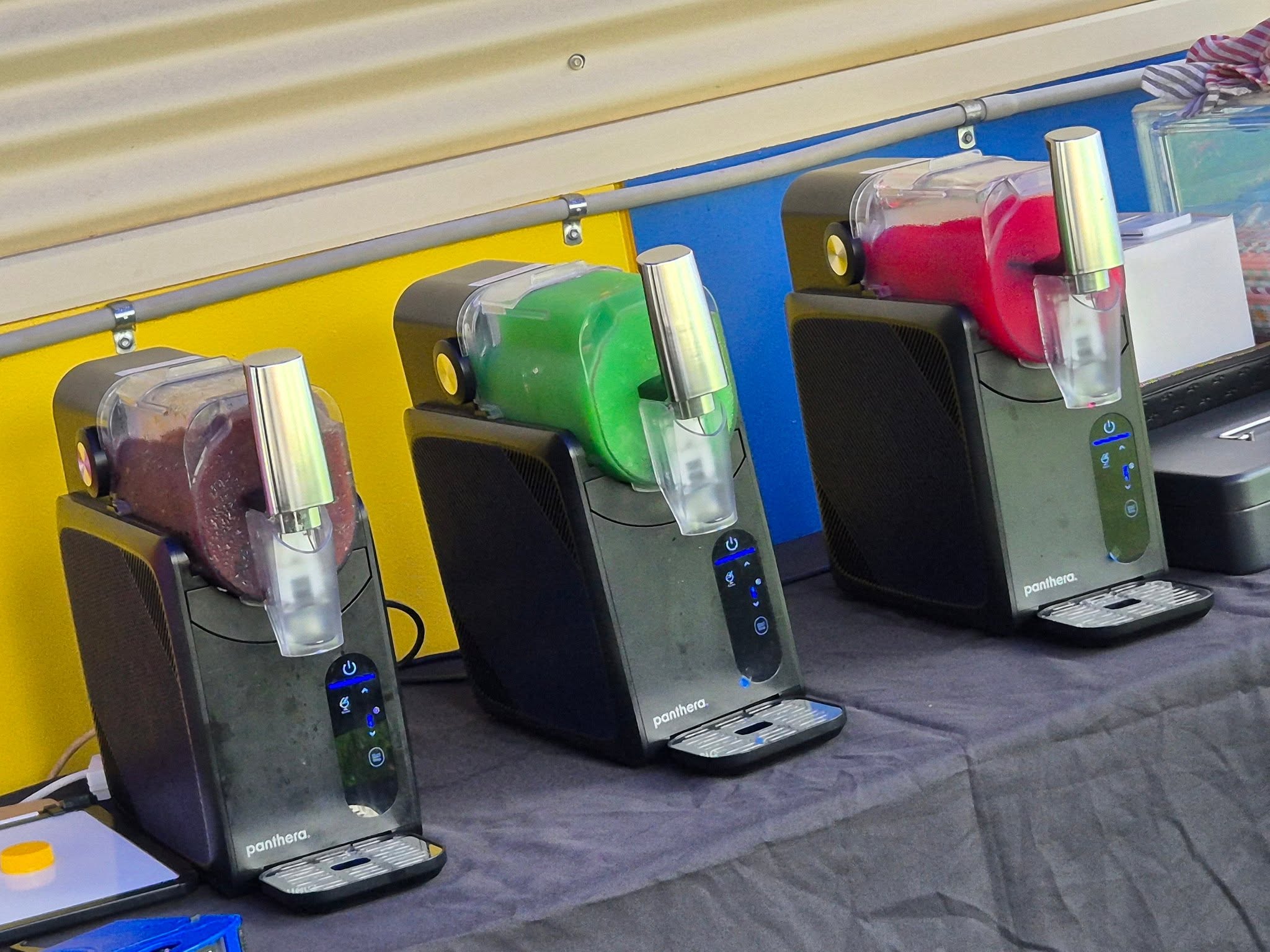 Three colourful countertop slushie machines